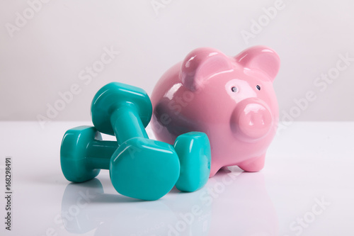 Green dumbbells with piggy bank for health insurance concept