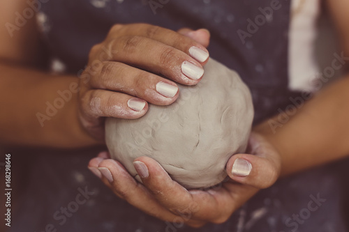 Female potter hands holds clay for pottery, selective focus