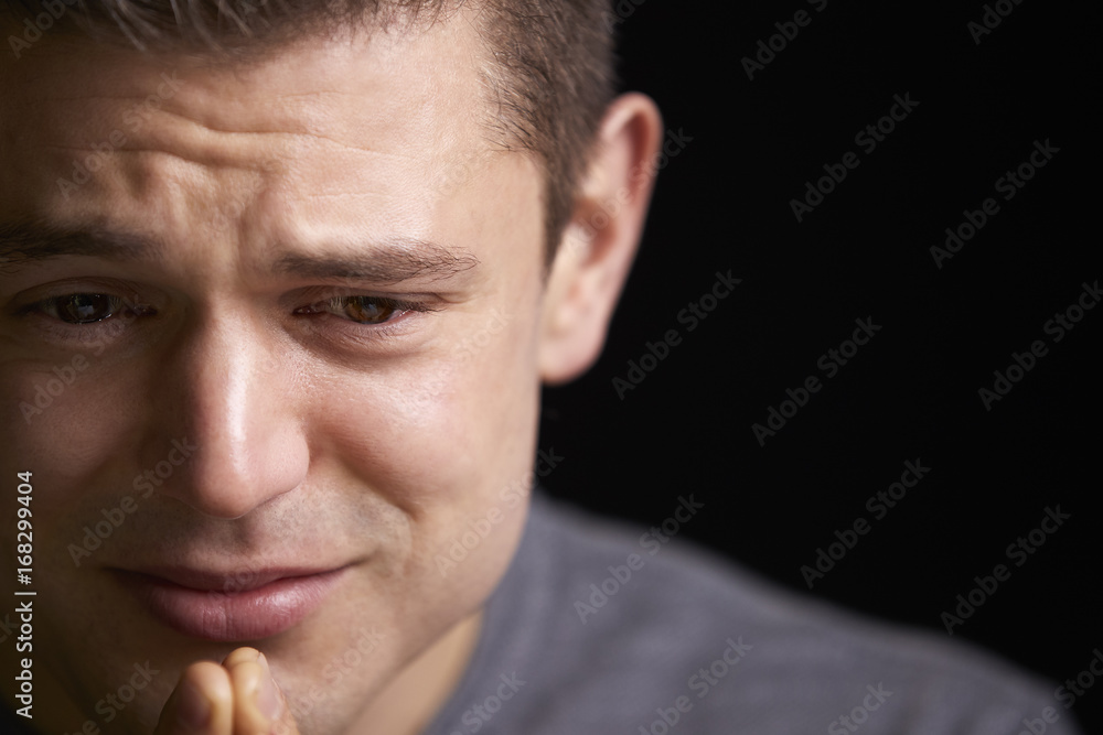 Fototapeta premium Close up of crying young white man looking down, horizontal