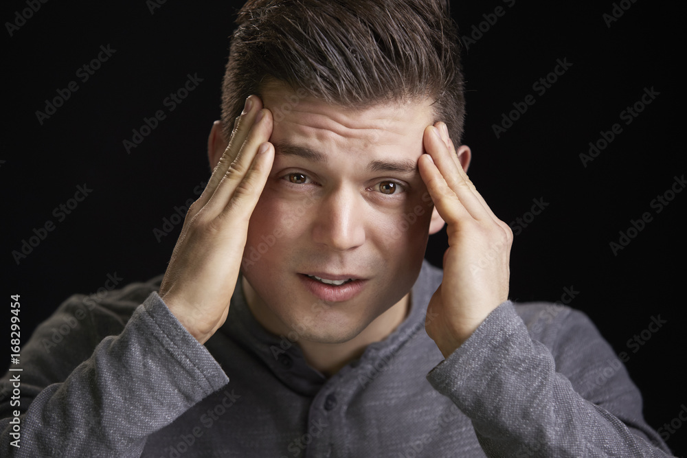Portrait of a worried young white man holding head Portrait of a worried young white man holding head