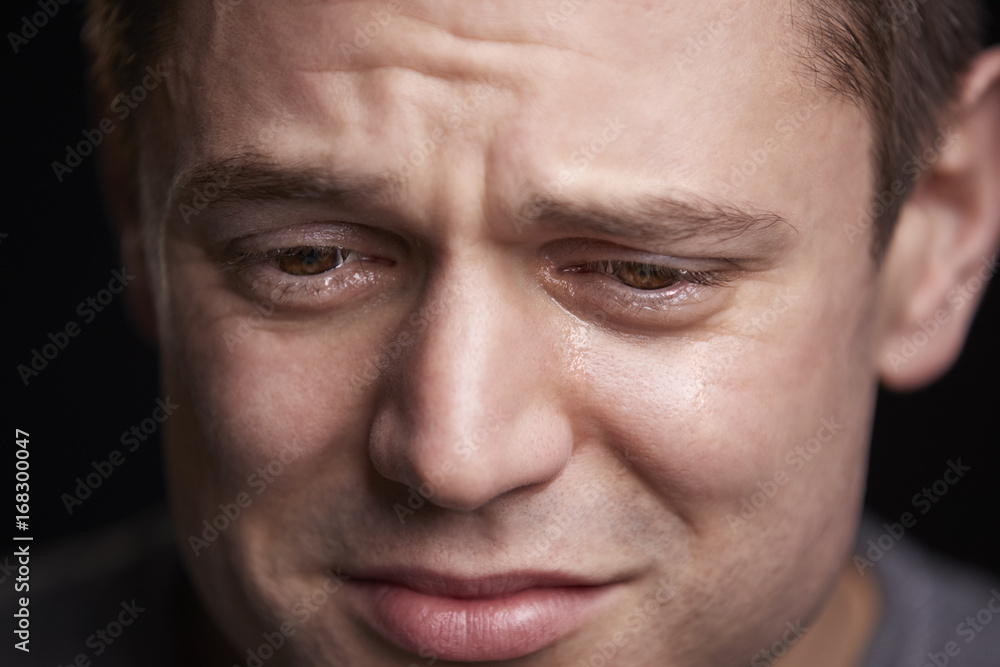 Close up portrait of crying young white man looking down Close up portrait of crying young white man looking down