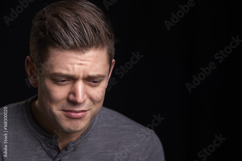 Portrait of crying young white man looking down