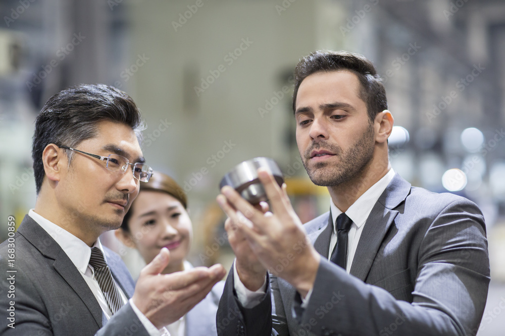 Business people checking machine parts in the factory Business people checking machine parts in the factory