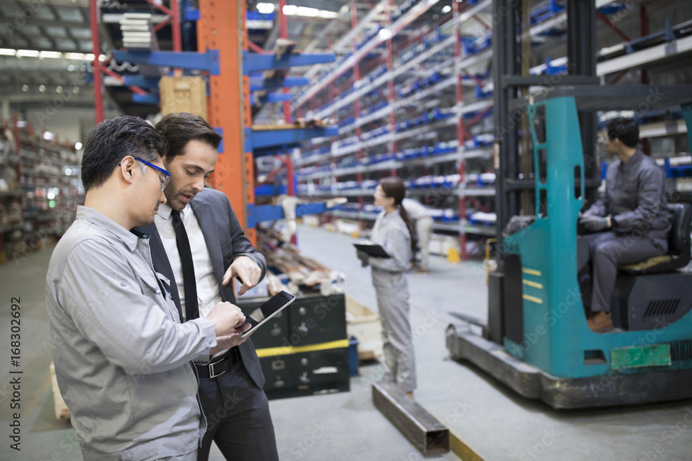 Businessman and engineer talking in the factory Businessman and engineer talking in the factory