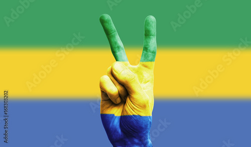 Gabon national flag painted onto a male hand showing a victory, peace, strength sign