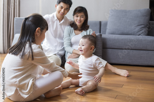 Happy young family sitting on wooden floor