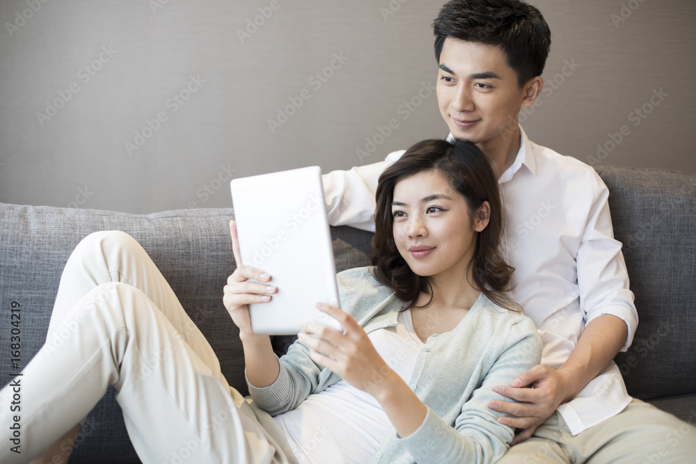 Cheerful young couple using digital tablet at home Cheerful young couple using digital tablet at home