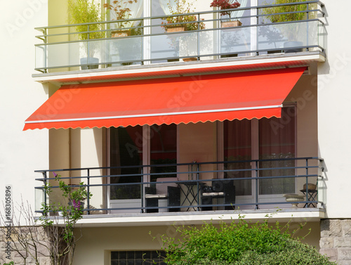 French balcony with awning opened covered by sun-shield on a warm summer day photo