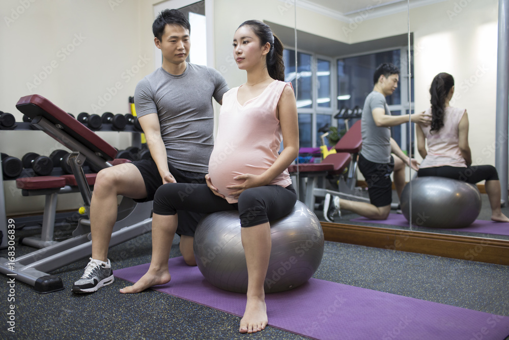 Pregnant woman working out with trainer in gym Pregnant woman working out with trainer in gym