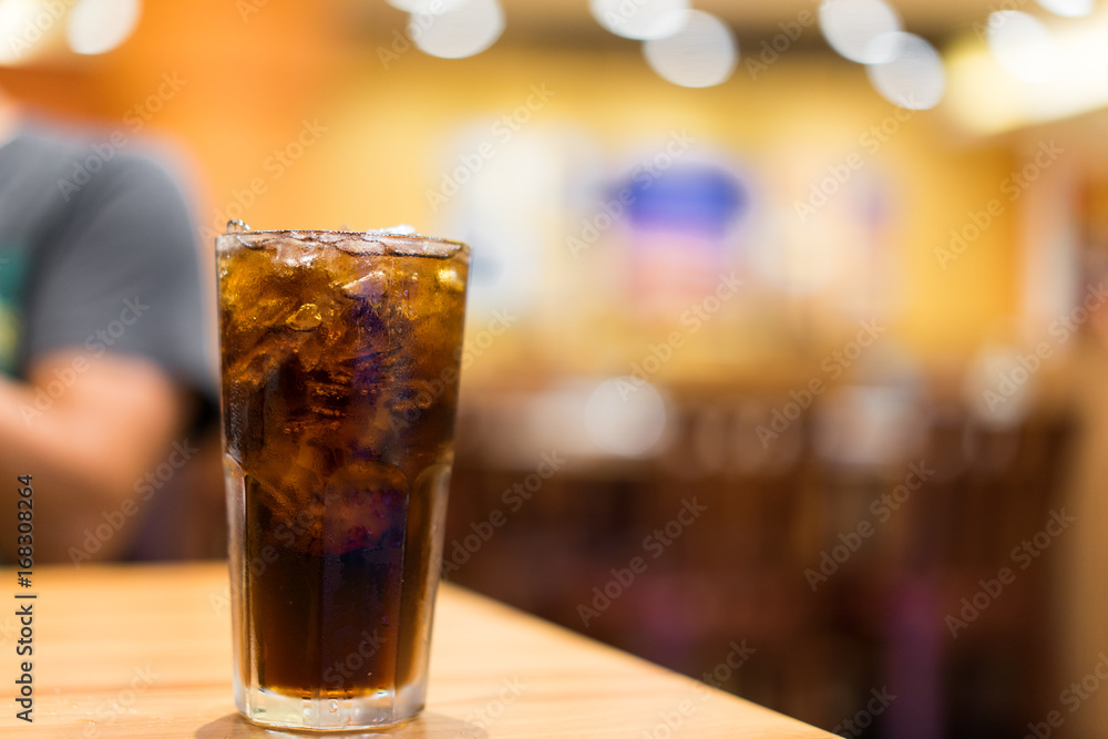 Cool ice soft drink cola carbonated liquid fresh food with soda water, white dish on wooden table with handsome man sitting  brown sofa in pizzeria restaurant.