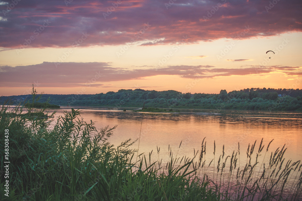 Fototapeta premium Summer sunset on the Oka river, with a flying paraglider