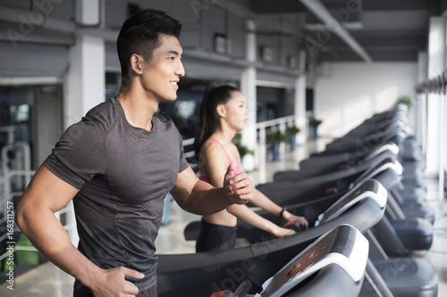 Young couple exercising on treadmills in gym photo