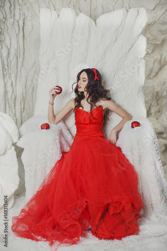 beautiful brunette in a scarlet dress in the snow with apples photo