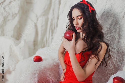 beautiful brunette in a scarlet dress in the snow with apples photo