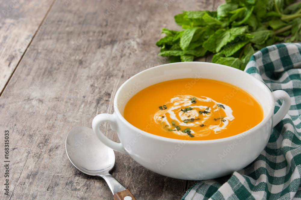 Pumpkin soup in white bowl on wooden table
Pumpkin soup in white bowl on wooden table