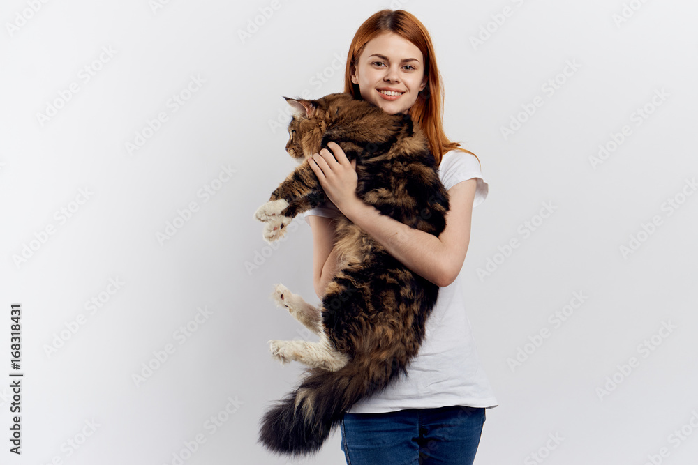 Young beautiful woman on a light background holds a cat, emotions, smile