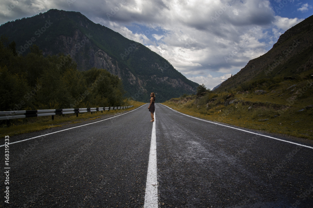 Fototapeta premium single barefoot woman is walking along the mountain road. Travel, tourism and people concept
