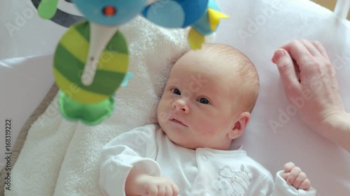 Newborn baby in crib. Hands young mother touching a newborn baby in a adle photo