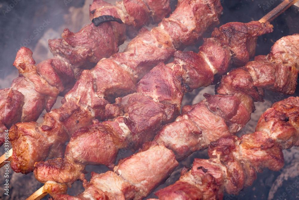 closeup of some meat skewers being grilled in a barbecue closeup of some meat skewers being grilled in a barbecue