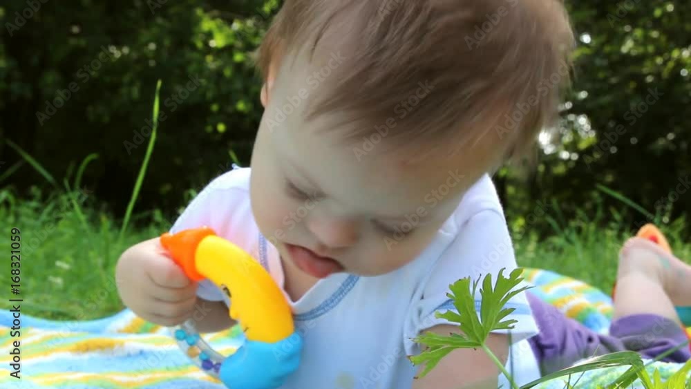 Portrait of Cute baby boy with Down syndrome lying on blanket in summer day on nature with toys Portrait of Cute baby boy with Down syndrome lying on blanket in summer day on nature with toys
