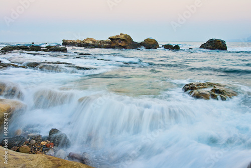 At sunset, waves come in over the rocks in northern Taiwan right next to Yehliu Geopark.