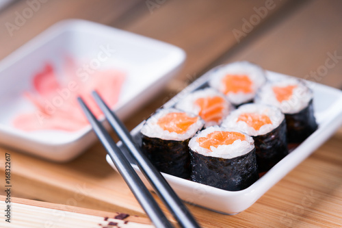 Foto Sushi rolls with salmon, ginger and chopsticks