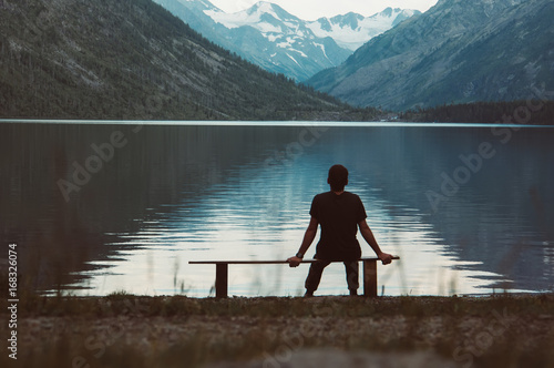 Bild auf Leinwand A lonely man sitting on the bench in front of the lake