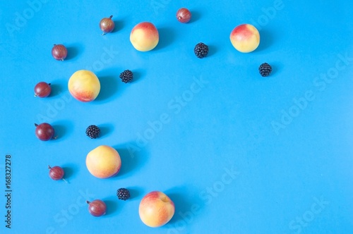 Summer fruit background  A pattern of summer berries. Gooseberries  red nectarines and blackberries on a blue background. Flat lay food photography  top view