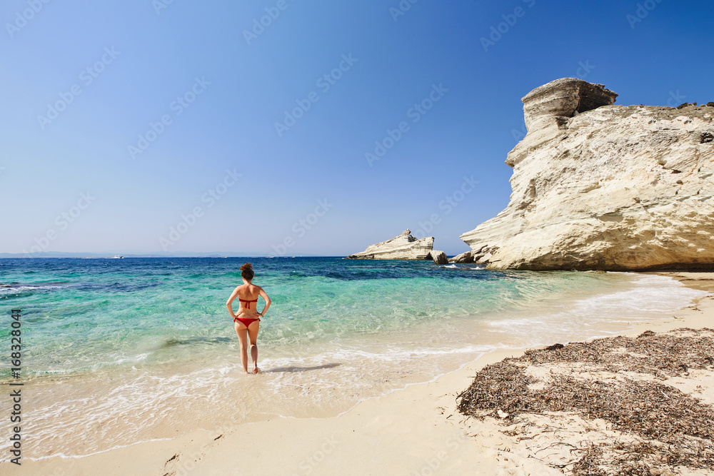 Ragazza con tanga rosso di spalle al mare in Corsica spiaggia bianca