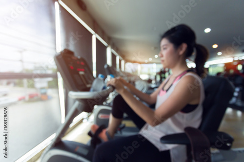 blurred woman cycling burn fat on bicycle cardio machine in fitness gym