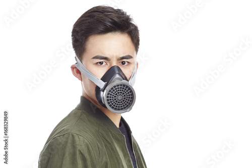 asian man wearing gas mask looking at camera, isolated on white background. 
