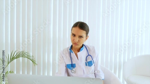 Young attractive female doctor doing selfie with a mobile phone Girl dressed as a doctor sitting in the office. She takes a photo on a cell phone.