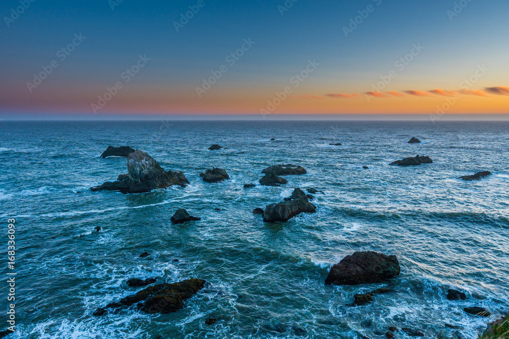 Obraz premium Marvellous sunset, amazing evening sky. Large boulder among the waves in the sea. Sonoma Coast State Park, California, USA