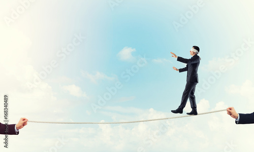 Business concept of risk support and assistance with man balancing on rope