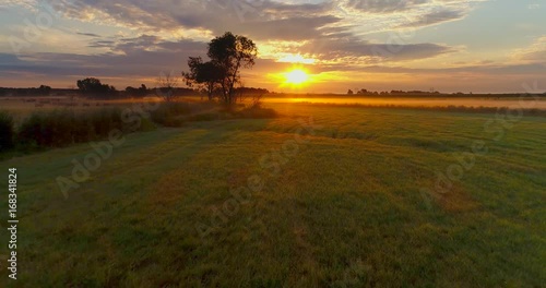 Amazing sunrise bursts through clouds over foggy Midwest farm fields.
