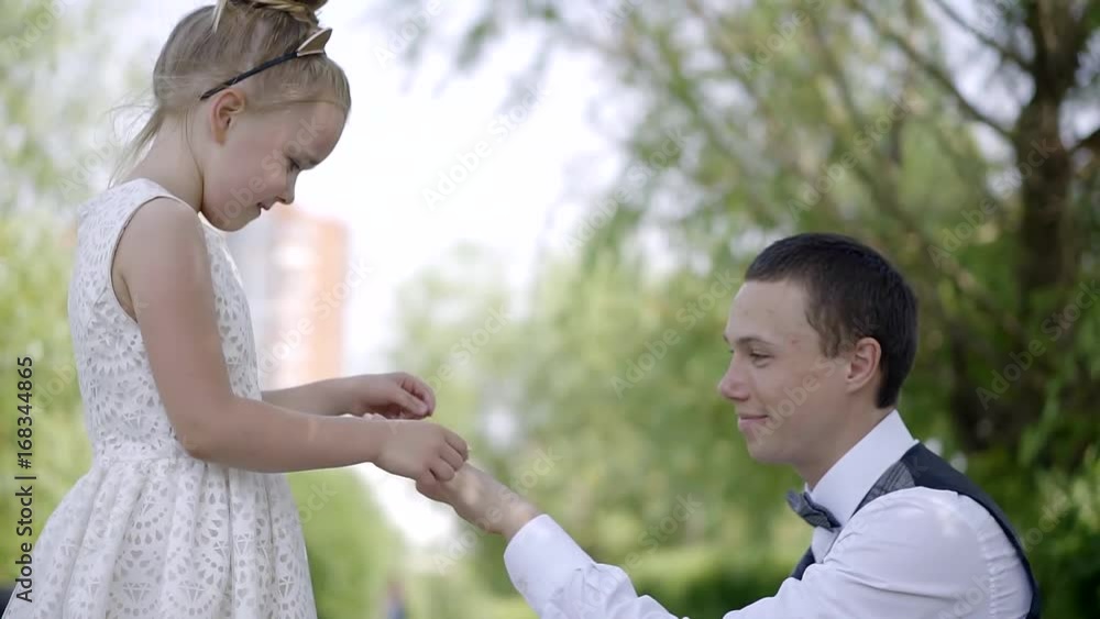 little girl with a headband on the hair in the ears cat wears a ring of clovers on the finger of the man. the boy hugs the baby and kisses her. happy people on the day of the wedding little girl with a headband on the hair in the ears cat wears a ring of clovers on the finger of the man. the boy hugs the baby and kisses her. happy people on the day of the wedding