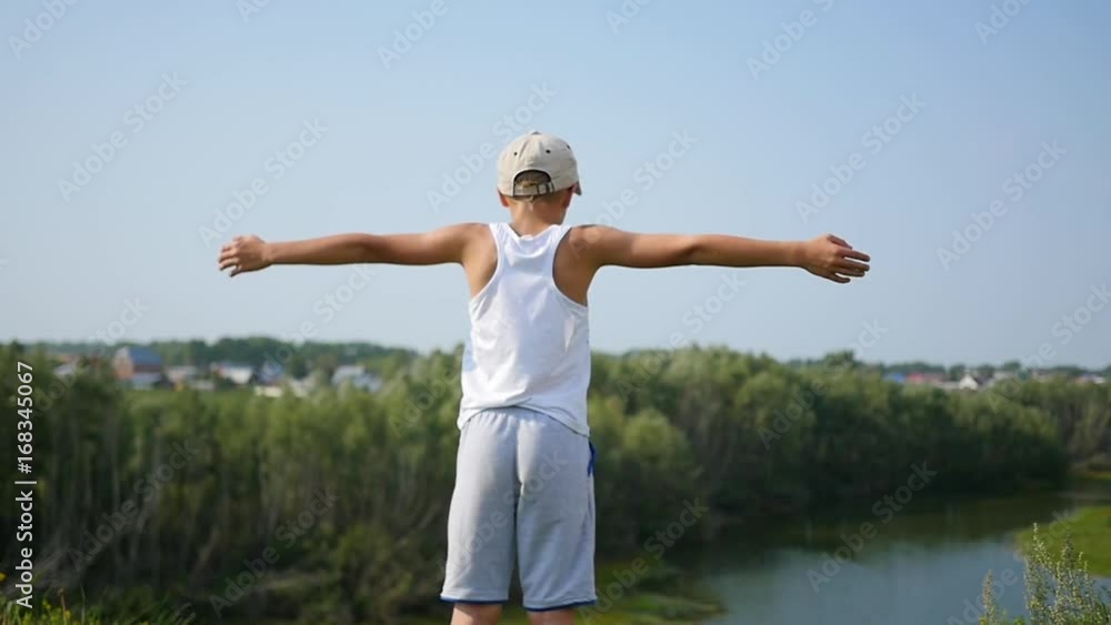 A young guy is standing on the river bank. Beautiful summer landscape A young guy is standing on the river bank. Beautiful summer landscape