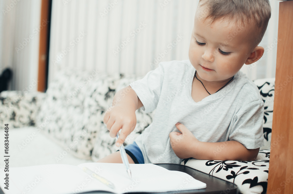 Little baby boy thoughtfully draws or writes pen Little baby boy thoughtfully draws or writes pen