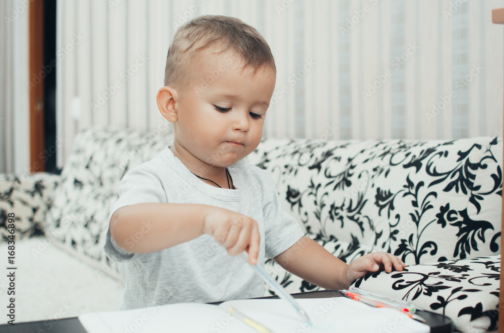 Little baby boy thoughtfully draws or writes pen Little baby boy thoughtfully draws or writes pen