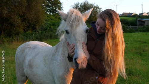 young woman and her horse at sunset in a field