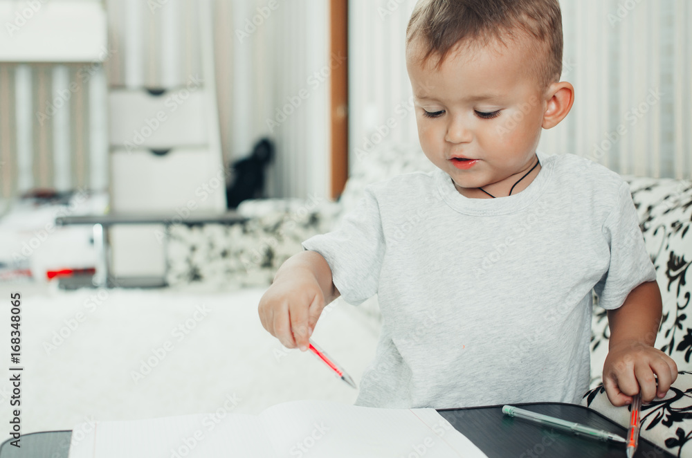 Little baby boy thoughtfully draws or writes pen Little baby boy thoughtfully draws or writes pen