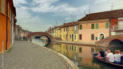romantic Venetian gondola in canal near typical colorful Italian houses in Italian lagoon town,  color graded clip