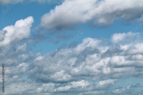 Altocumulus puffy white clouds against a light azure sky