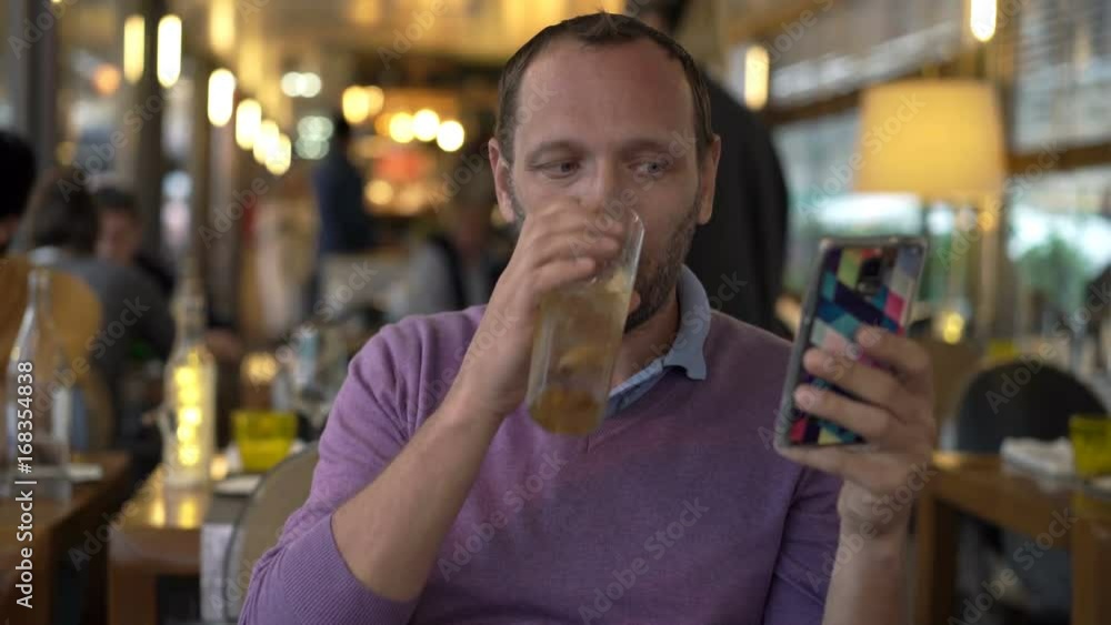 Young man texting on smartphone and drinking cocktail in cafe
Young man texting on smartphone and drinking cocktail in cafe