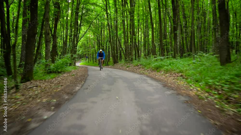 Middle-aged man is riding a road bike along a forest road Middle-aged man is riding a road bike along a forest road