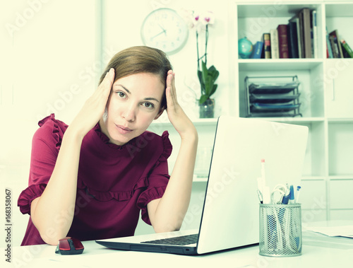 Thoughtful woman working with laptop