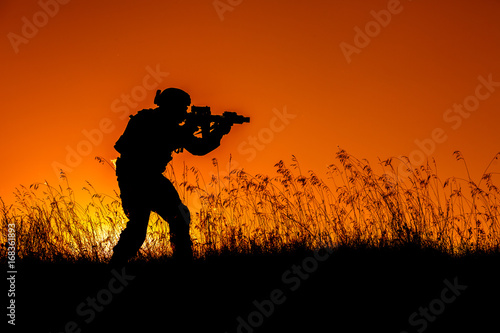 military soldier with weapons at sunset. shot, holding gun, colorful sky. military concept.