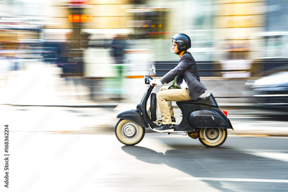 Naklejka premium Mężczyzna jedzie motorowerem wzdłuż ulicy