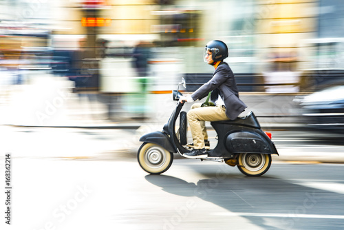 A man is riding a moped along the street
