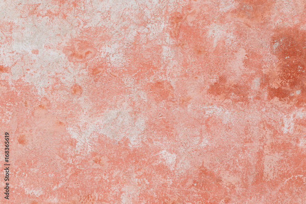 Close-up of a weathered and aged concrete wall, bleached red paint partly peeled off. Texture background.